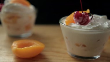 Ahşap zemin üzerinde siyah arka planda şeftali ve krema bardakları