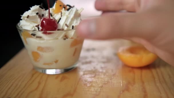 Hand grabbing cup of peaches and cream from wooden surface — Stock Video