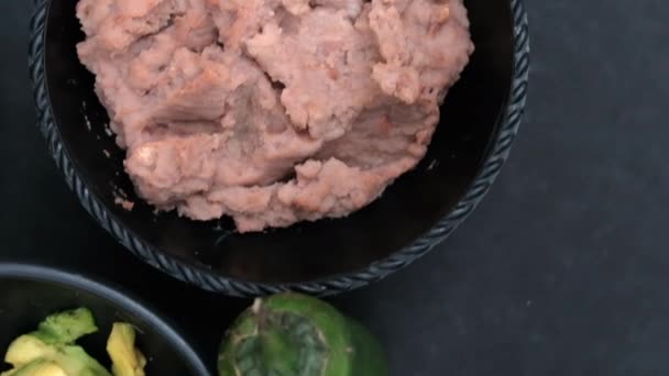 Pimenta de pimentão encostada a tigelas de abacate picado e feijão frito — Vídeo de Stock