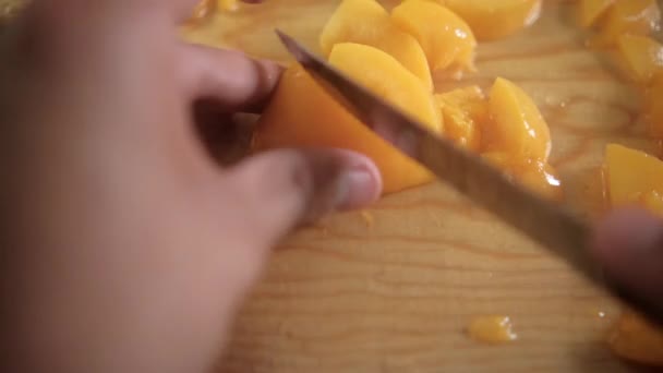 Händer skivade persikor på en skärbräda — Stockvideo