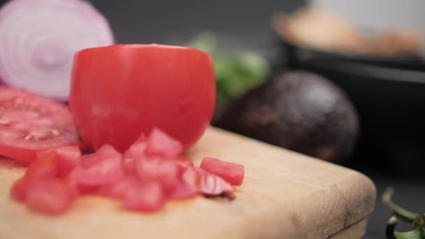 Gesneden tomaat en ui op houten snijplank met wazige ondergrond — Stockvideo