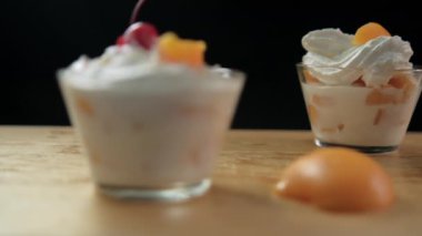 Ahşap zemin üzerinde siyah arka planda şeftali ve krema bardakları