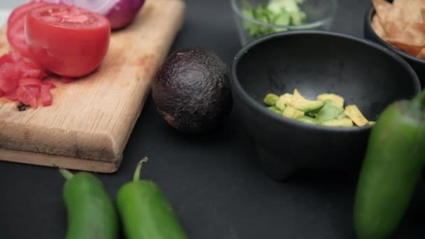 Papryka chili i miski posiekanych awokado i wiórów tortilla na czarnej powierzchni — Wideo stockowe