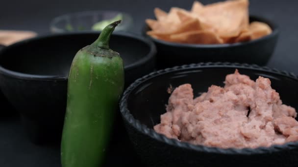 Pimenta de pimentão encostada a tigelas de tortilla e feijão frito — Vídeo de Stock