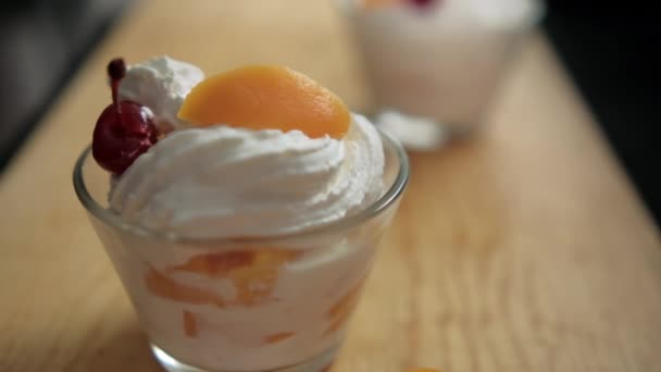 Cups of peaches and cream on wooden surface with black background — Stock Video