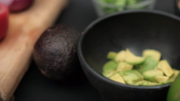 Chiles y tazones de aguacate picado y frijoles refritos en superficie negra — Vídeos de Stock