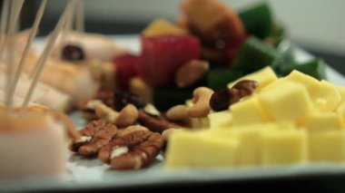 Jambonlu dürüm, meyve ezmesi, peynir küpü, fındık, beyaz tabakta kuru kızılcık.