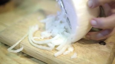 Eller dikkatlice odun kesme tahtasının üzerinde soğan doğruyor.
