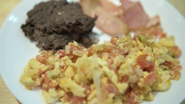 Huevos al estilo mexicano, tocino y frijoles refritos en un plato blanco — Vídeos de Stock