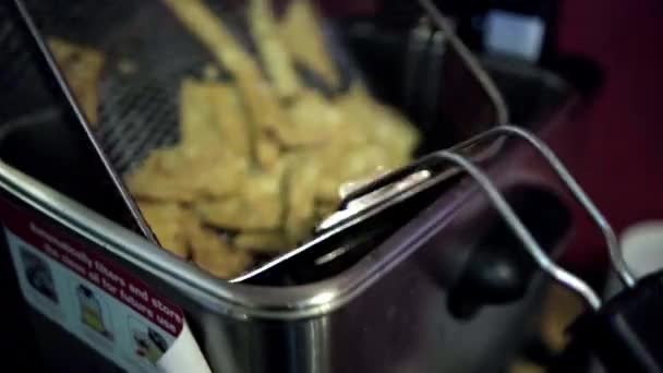 Ręczne umieszczanie kosza frytkownicy z chipsami tortilla nad wrzącym olejem — Wideo stockowe