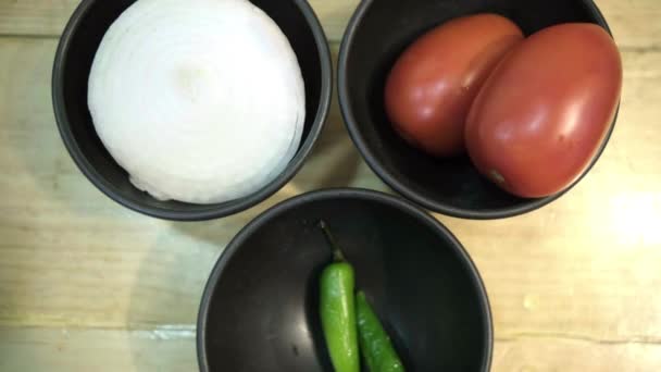 Tomates, cebolla y chiles en tazones negros por encima de la superficie de madera — Vídeos de Stock