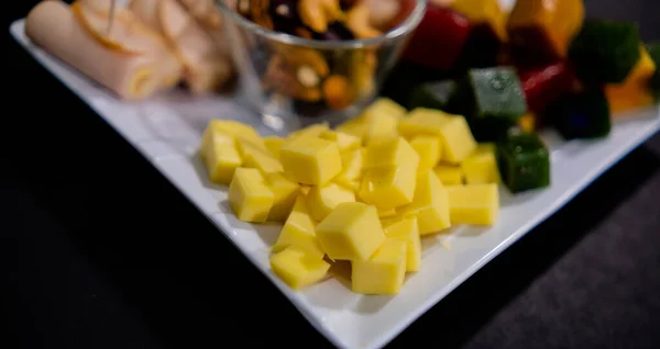 Šunkové závitky, nakrájená ovocná pasta, kostky sýra a ořechy na čtvercový bílý talíř — Stock fotografie