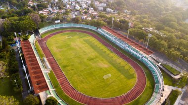 Evler ve ağaçlarla çevrili koşu pisti ve futbol sahasının havadan görünüşü