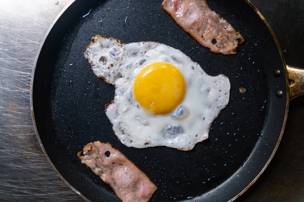 Utsökt stekt ägg och baconremsor på stekpanna — Stockfoto