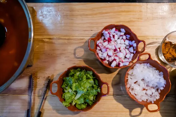 Délicieux pozole traditionnel mexicain, laitue et condiments sur table en bois — Photo