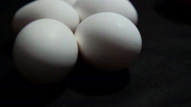 Siyah yüzeyde yatan beş taze beyaz yumurta.