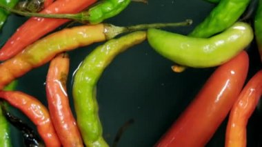 Renkli ince ve taze kırmızı biberler suyun üzerinde yüzüyor.