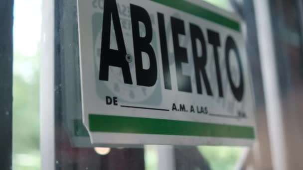 Zielono-biały znak z otwartym słowem w języku hiszpańskim na oknie — Wideo stockowe