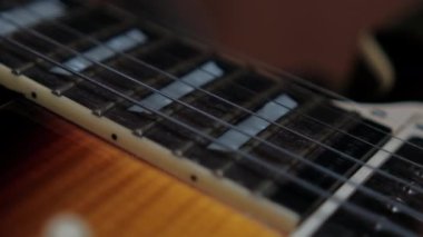 Kolunun üstünde titreşen klasik elektro gitar dizileri ve perdeler.