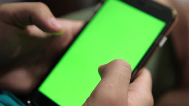 Parlak yeşil ekranlı siyah bir akıllı telefon tutan eller. — Stok video