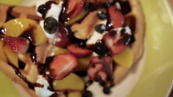 Leckere aufgeschnittene Waffel mit Sahne, Fruchtscheiben und Schokoladensirup obendrauf — Stockvideo