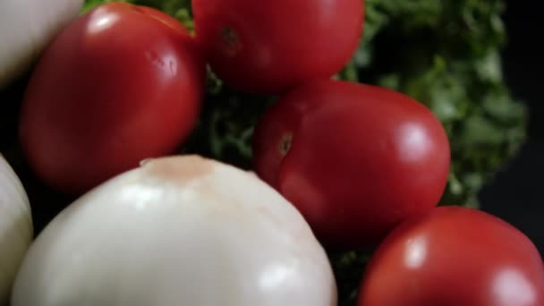 Zwiebeln, frische Tomaten und großer Salat vor schwarzem Hintergrund — Stockvideo