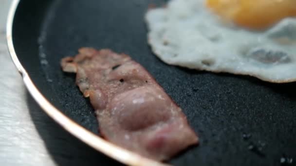 Ovo frito delicioso e tira de bacon em uma panela de ato de fritar — Vídeo de Stock