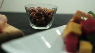 Hindi jambonlu rulo, doğranmış meyve ezmesi ve siyah bir yüzeyde fındık.