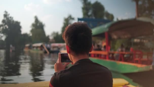 Jongeman opnemen van de Xochimilco meer en Mexicaanse trajineras met zijn telefoon — Stockvideo