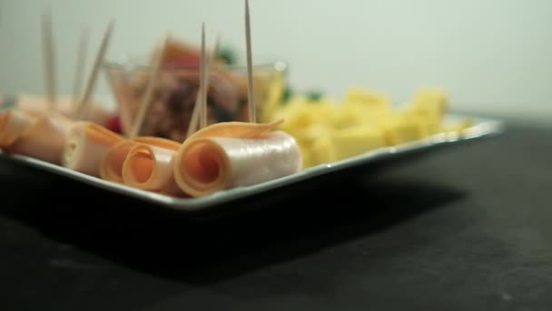 Schinkenröllchen, Fruchtpüree, Käsewürfel und Nüsse auf einem weißen Teller — Stockvideo