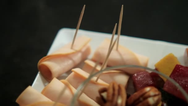 Schinkenröllchen, Fruchtpüree, Käsewürfel und Nüsse auf einem weißen Teller — Stockvideo