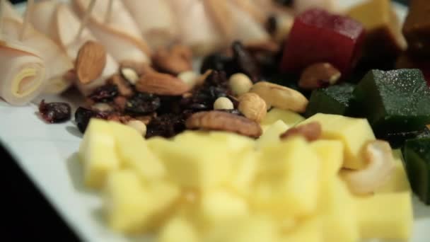 Ham gulung, pasta buah, keju batu, kacang-kacangan, cranberry kering di piring putih — Stok Video