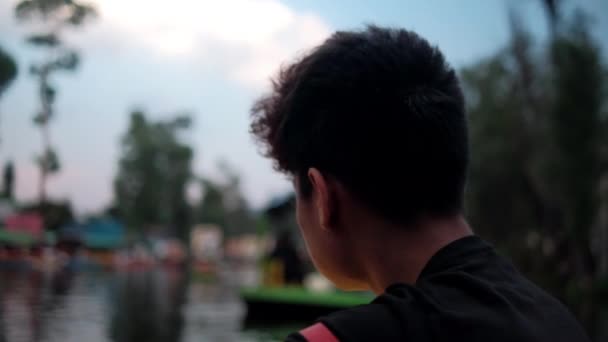 Young man looking at the Xochimilco lake and Mexican trajineras — Stock Video