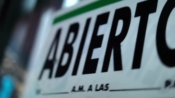 Signo verde y blanco con la palabra abierta en español balanceándose en la ventana — Vídeo de stock
