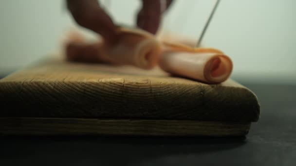 Händer plocka kalkon skinka rullar med tandpetare ovanför skärbräda — Stockvideo