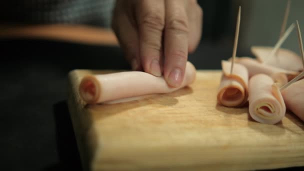 Händer skivning kalkon skinka rullar med tandpetare ovanför skärbrädan — Stockvideo