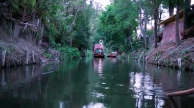 Xochimilco gölünde ağaçlarla çevrili geleneksel renkli trajinera