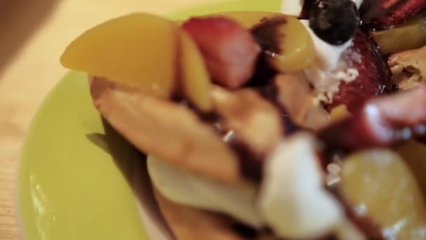 Delicioso waffle fatiado com creme, fatias de frutas e xarope de chocolate em cima — Vídeo de Stock