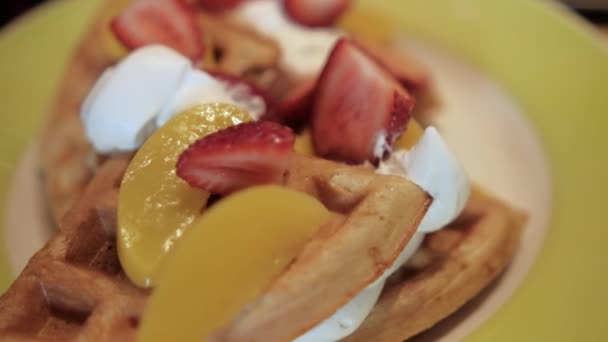 Delicioso waffle fatiado com fatias de creme e frutas em cima — Vídeo de Stock