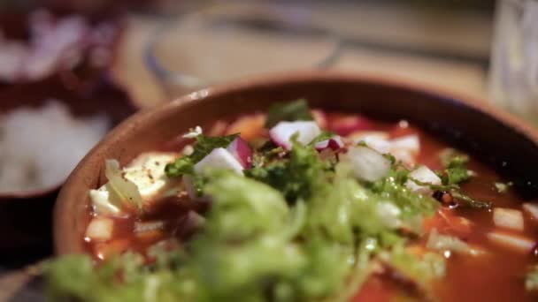 Tazón de barro de delicioso y tradicional pozole mexicano sobre mesa de madera — Vídeos de Stock