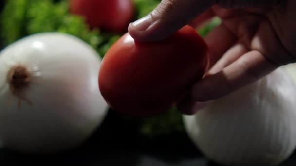 Χέρι κρατώντας ντομάτα μπροστά από μεγάλο φρέσκο μαρούλι και κρεμμύδια — Αρχείο Βίντεο