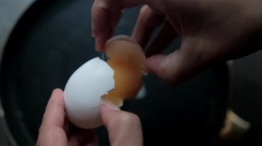 Eller yavaşça tavaya yumurta kırıyor.
