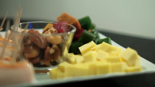 Rotoli di prosciutto, pasta di frutta a dadini, cubetti di formaggio e noci su un piatto bianco — Video Stock