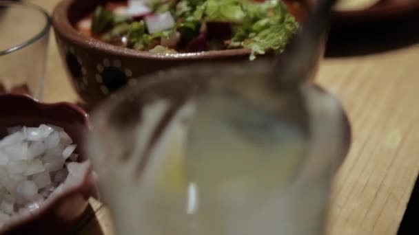 Pyszne tradycyjne meksykańskie pozole i przyprawy na drewnianym stole — Wideo stockowe