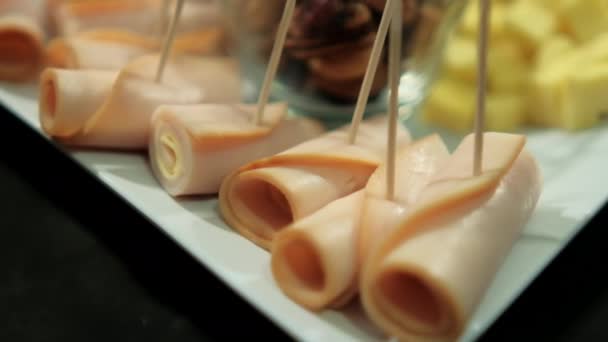 Vaso de nueces rodeado de rollos de jamón, pasta de frutas en cubitos y cubos de queso — Vídeo de stock