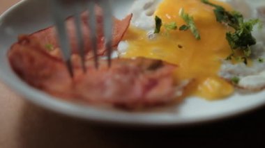 Çatal, tabaktan lezzetli pastırma parçaları ve kızarmış yumurta ve doğranmış otlar topluyor.