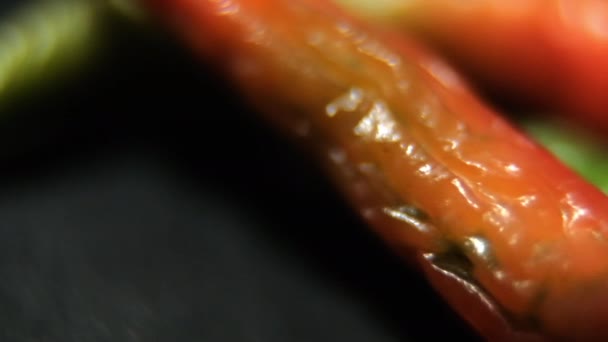 Close-up de pimentas finas e frescas coloridas na superfície preta — Vídeo de Stock