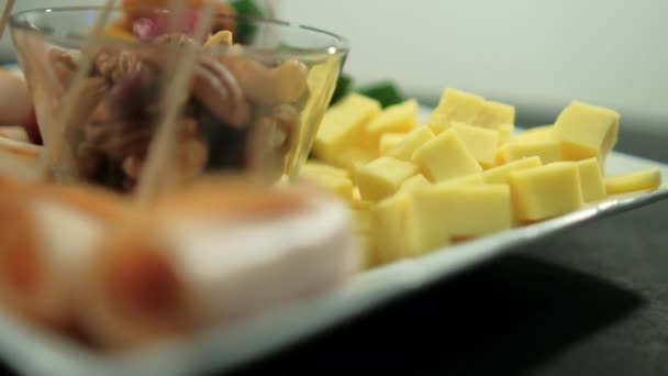 Rollos de jamón, pasta de frutas en cubitos, cubos de queso y nueces en un plato blanco — Vídeos de Stock