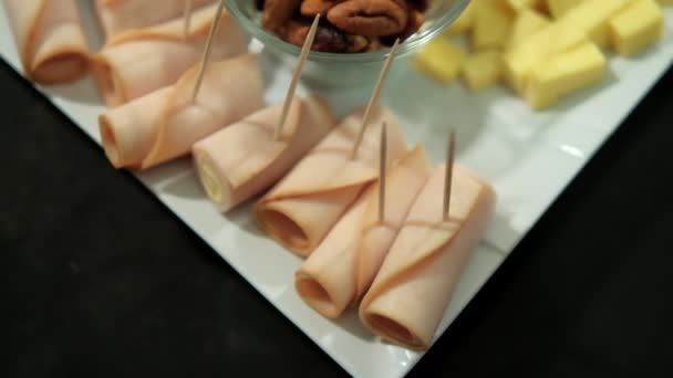 Rollos de jamón, pasta de frutas en cubitos, cubos de queso y nueces en un plato blanco — Vídeo de stock