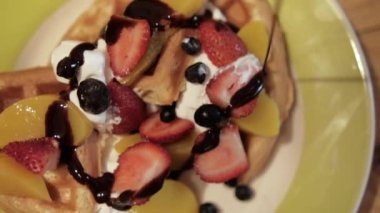 Lezzetli dilimlenmiş kremalı waffle, meyve dilimleri ve üstüne çikolata sosu.